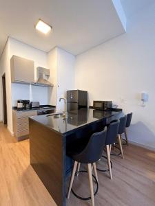 a kitchen with a counter and chairs in a room at Edificio M1 - Apartamentos frente a Punta Carretas Shopping - Gym Laundry Parrillero Solarium in Montevideo