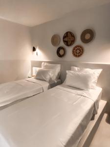2 camas blancas en una habitación con platos en la pared en Pilos Suites en Turunc