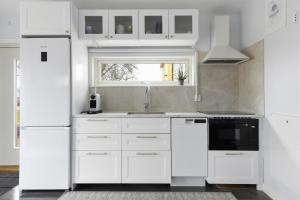 a white kitchen with white appliances and a window at Park House Gävle - a modern renovated house in the park - 5A in Gävle