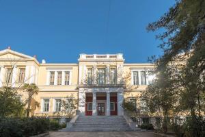 un gran edificio amarillo con escaleras delante en Ermis exclusive apt in Kolonaki, en Atenas