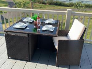 an outdoor table with wine glasses and napkins on a deck at The Wardens Retreat - Tattershall Lakes Country Park in Tattershall