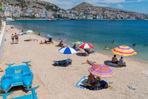 a group of people on a beach with umbrellas at DEA Room 1 in Sarandë +3 photos