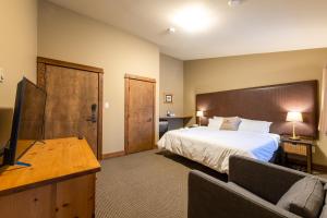 ein Hotelzimmer mit einem Bett und einem Flachbild-TV in der Unterkunft Copper Horse Lodge in Golden