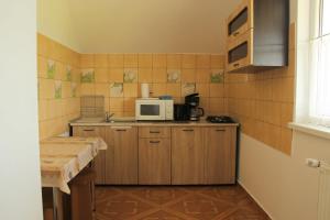 eine kleine Küche mit Holzschränken und einer Mikrowelle in der Unterkunft SZÁSZ&SZÁSZ PANZIÓ in Gheorgheni