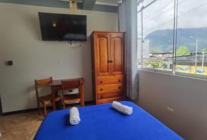 a bedroom with a blue bed and a window at Hotel Su Majestad in Tingo María