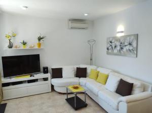 een woonkamer met een witte bank en een flatscreen-tv bij House Anna in Sobra