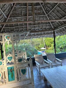 une chambre avec des chaises, une table et un toit dans l'établissement WHITE Nyumba, à Malindi