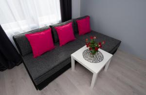 - un canapé noir avec des oreillers roses et une table blanche dans l'établissement Apartament blisko ZOO, Orientarium oraz Atlas Areny, à Łódź