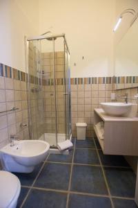 a bathroom with a shower and two sinks and a toilet at La Giara Resort in Torre San Giovanni Ugento