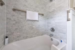 a white bath tub in a bathroom with a tile wall at Garden Getaway - Walking Distance to downtown Douglas - Cute Home! in Douglas +22 photos