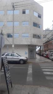 un coche aparcado en un aparcamiento frente a un edificio en HOTEL JIMENA en Iquique
