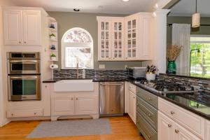 Una cocina con gabinetes blancos y un fregadero. en Idle Hour - Updated Home 2 blocks to South Beach and Town, en South Haven