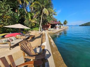 una playa con sillas y un cuerpo de agua en Pousada e Mergulho Jamanta en Angra dos Reis
