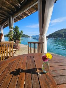 a vase of flowers sitting on a wooden table on the beach at Pousada e Mergulho Jamanta in Angra dos Reis