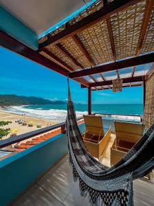 a hammock on a balcony with a view of the beach at Hotel Garni Cruzeiro do Sul in Paraty