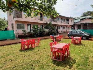 a group of red chairs and a table in a yard at Swami Leela Relax Inn in Mahabaleshwar