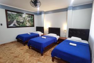 Habitación con 3 camas y sábanas azules. en Hotel Su Majestad en Tingo María