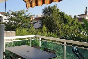 een tafel en stoelen op een balkon met bomen bij Terrasse ensoleillée et accès à la piscine vue mer in Vallauris