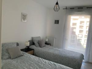 une chambre avec deux lits et une fenêtre dans l'établissement Logement cosy climatisé avec parking, à Aix-en-Provence