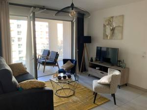 un salon avec un canapé, des chaises et une télévision dans l'établissement Logement cosy climatisé avec parking, à Aix-en-Provence