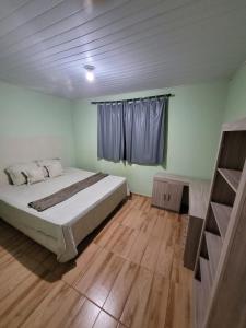 Schlafzimmer mit einem Bett, einem Fenster und Holzböden in der Unterkunft Casa em São Lourenço in São Lourenço
