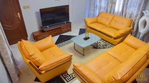 ein Wohnzimmer mit orangefarbenen Sofas und einem TV in der Unterkunft Dreams hotel in Douala