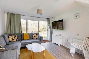 una sala de estar con un sofá y una mesa en Beach Woods Coastal Path chalet, en Pembrokeshire