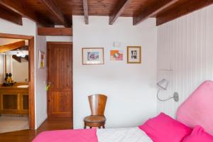 ein Schlafzimmer mit einem rosa Bett und einem Stuhl in der Unterkunft Habitaciones Estrella del Norte in Santander