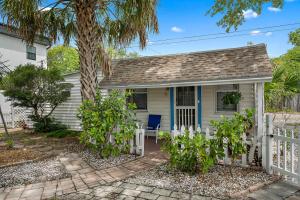 a small cottage with a white fence and a palm tree at Little Pineapple Cottage in St. Petersburg