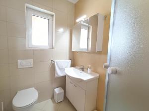 a white bathroom with a toilet and a sink at Haus Mit Meerblick in Lopar +97 photos