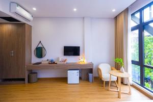 a room with a desk and a tv on a wall at Tropic Bloom Hotel in Móng Cái
