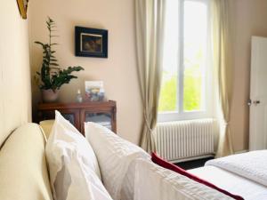 Schlafzimmer mit einem Bett mit weißer Bettwäsche und einem Fenster in der Unterkunft Le Manoir des Doyens in Bayeux