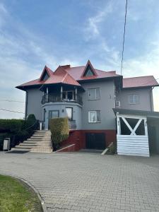 Casa blanca con techo rojo y entrada en Zajazd Restauracja Derby, en Błonie