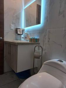 a bathroom with a toilet and a sink with a blue light at Departamento con jacuzzi 5 piso Condado 2 habitaciones in Quito