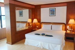 ein Schlafzimmer mit einem großen weißen Bett in einem Zimmer in der Unterkunft Grand Park Hotel in Nakhon Si Thammarat