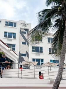 a white building with palm trees in front of it at The Tryst Beachfront Hotel in San Juan
