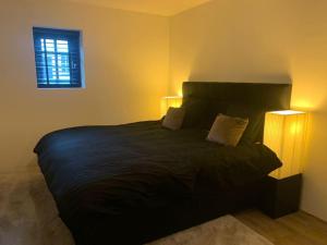a bedroom with a large black bed with two lamps at tuinhuis in Harmelen