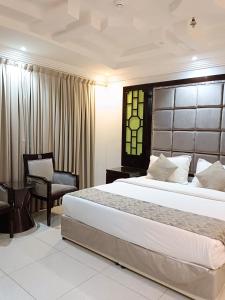 Aldar Hotel في جازان: غرفة نوم بسرير كبير وكرسي