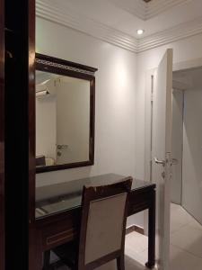 a bathroom with a mirror and a desk with a chair at Aldar Hotel in Jazan