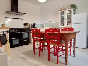 cocina con mesa de madera y sillas rojas en A Cèdre de mon enfance, en Vers Pont du Gard