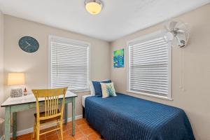 1 dormitorio con cama, escritorio y reloj en The Pineapple Bungalow St Pete, en San Petersburgo