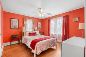 Un dormitorio con paredes naranjas y una cama y un ventilador de techo. en The Pineapple Bungalow St Pete, en San Petersburgo