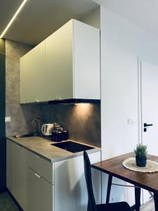 a kitchen with white cabinets and a wooden table at Enes Apartments Legnicka Street 59D in Wrocław