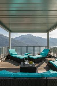 une terrasse avec des chaises, des tables et des montagnes bleues dans l'établissement Stairway to Heaven - Pianello del Lario by LoveComo, à Pianello Del Lario