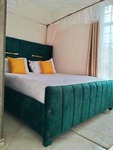 a large bed with a green headboard in a room at Yalacosy homes in Kitengela 