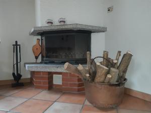 a fireplace with a bucket of wood in front of it at Rustico Rosso di Ribia 