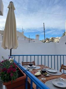 einen Tisch mit Gläsern Wein und einem Sonnenschirm auf dem Balkon in der Unterkunft Casa Blue in Torrox