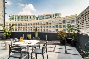 eine Terrasse mit einem Tisch und Stühlen sowie ein Gebäude in der Unterkunft ULIV Antara in Mexiko-Stadt