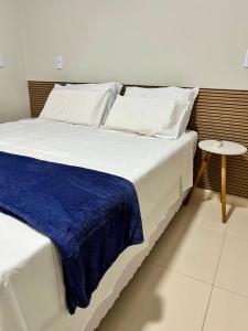 a large white bed with a blue blanket on it at Chalé Travosa in Santo Amaro