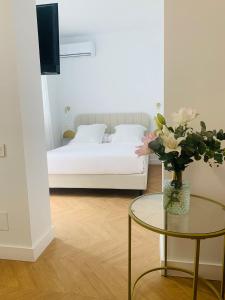um quarto com uma cama e uma mesa com um vaso de flores em Casa del Azucar em Motril